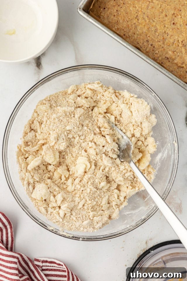 Overhead view of crumb topping mixture in a mixing bowl, showing its texture created with a fork