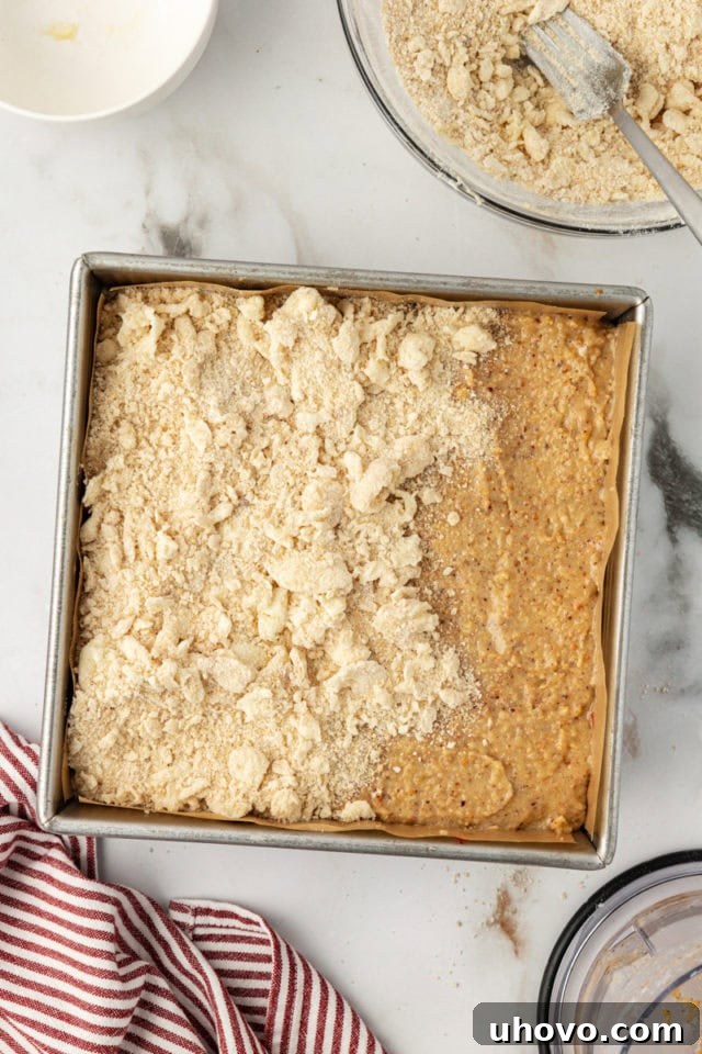 Overhead view of crumb layer being evenly added to the raspberry crumble bars