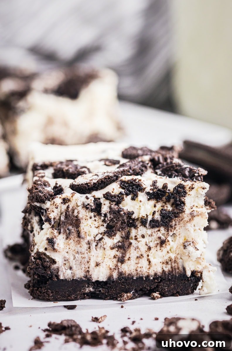 an Oreo cheesecake bar on a white surface with more bars in the background