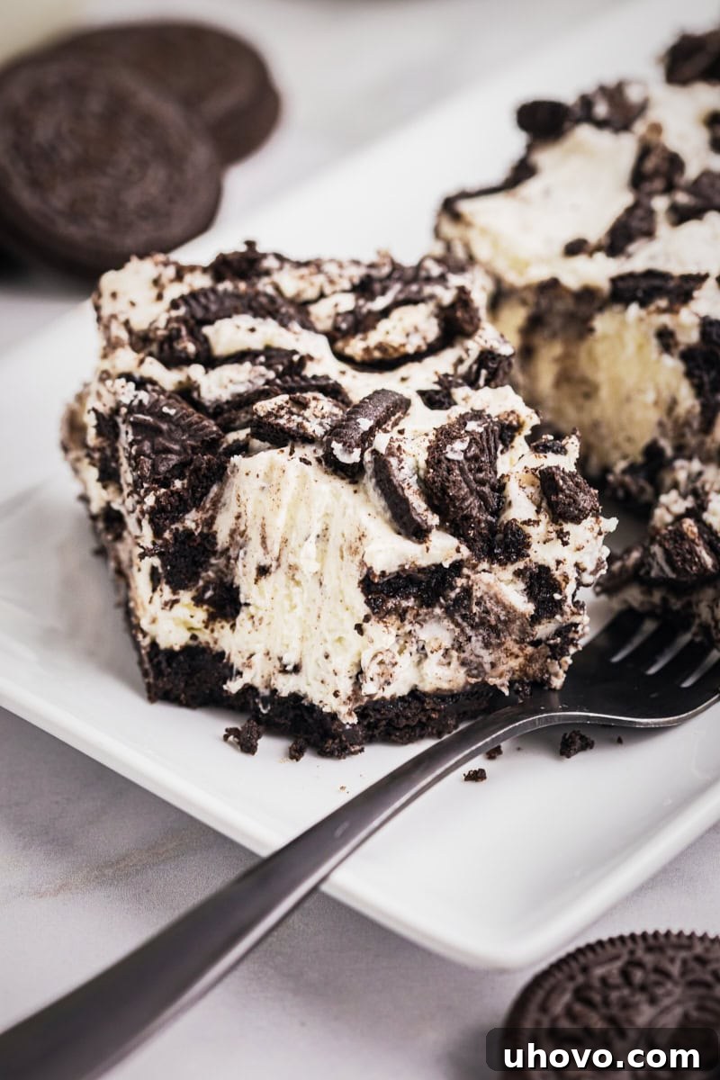 an Oreo cheesecake bar on a white plate with a bite on a fork