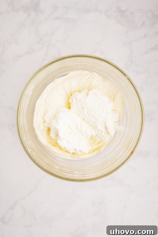 overhead view of whipped cream added to sweetened cream cheese mixture