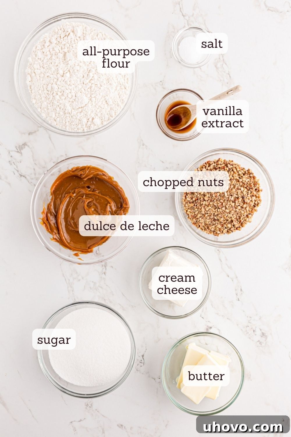 Overhead view of fresh ingredients for cream cheese shortbread, including flour, butter, cream cheese, sugar, and pecans.