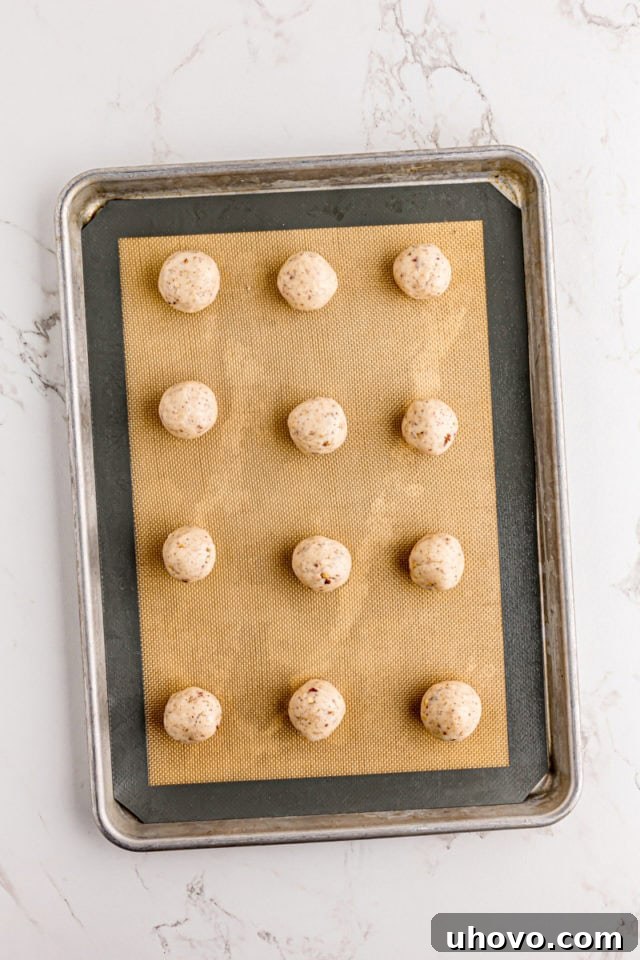 Evenly portioned cream cheese shortbread dough balls arranged on a parchment-lined baking sheet.