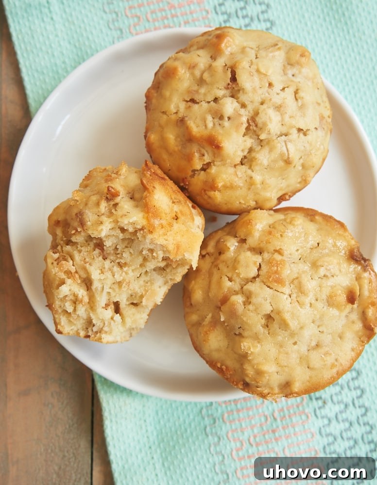 A serving of Coconut Cream Cheese Oat Muffins on a white plate, showcasing their rustic appeal and inviting texture, with some crumbs visible around.