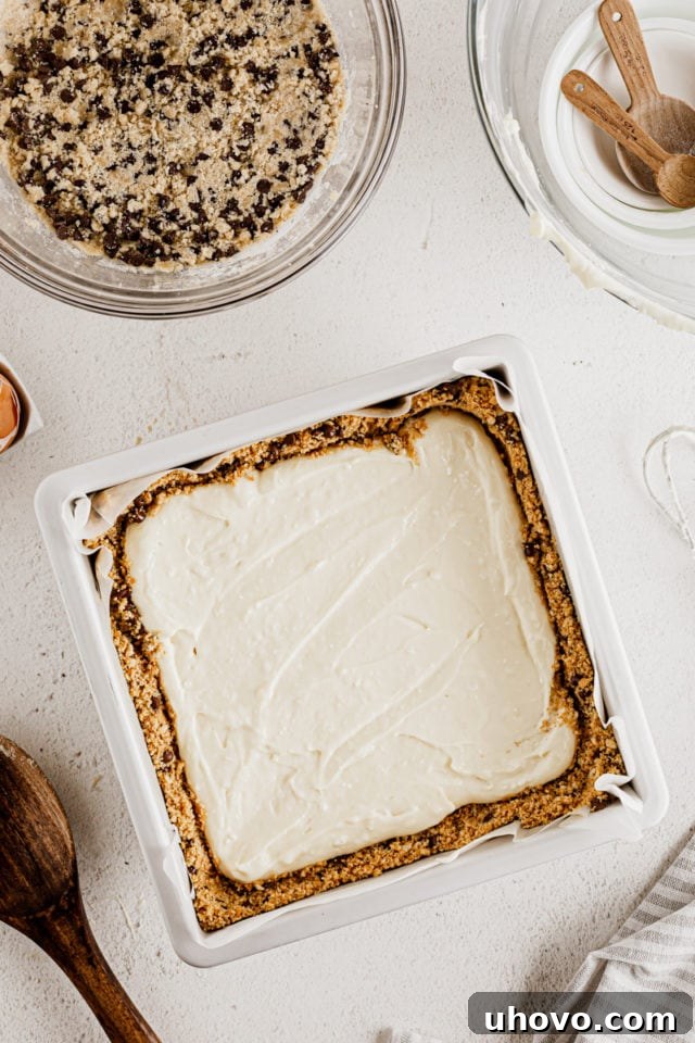Overhead view of cheesecake bars in pan before topping with cookie dough