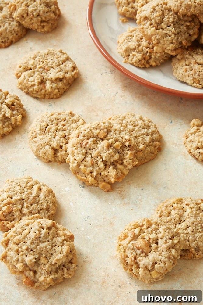 A generous scattering of golden Salted Cashew Crunch Cookies on a light beige surface, highlighting their appealing texture.