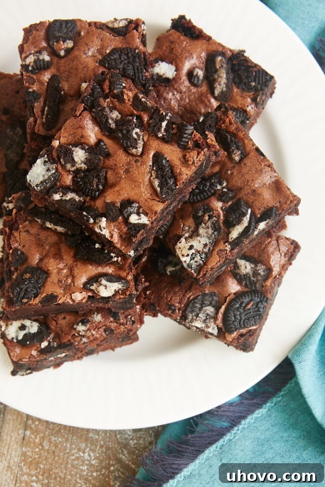 Overhead view of a tray of Fudgy Cookies and Cream Brownies, some cut into squares, showcasing the generous distribution of cookie pieces and their rich, dark surface.