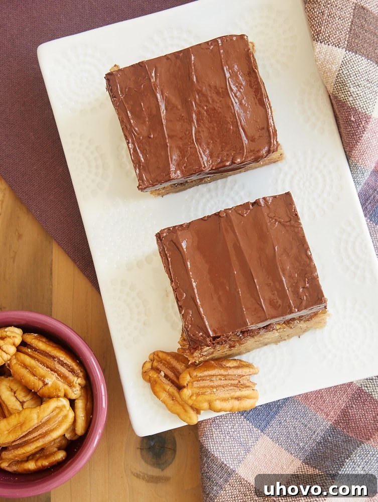 Close-up of a Pecan Sandie Praline Bar showing the thick cookie base, gooey pecan topping, and chocolate drizzle. A perfect homemade dessert.