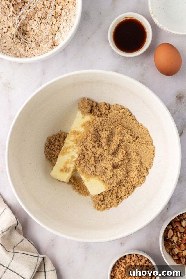 Overhead view of softened unsalted butter and brown sugar in a mixing bowl, before being creamed.
