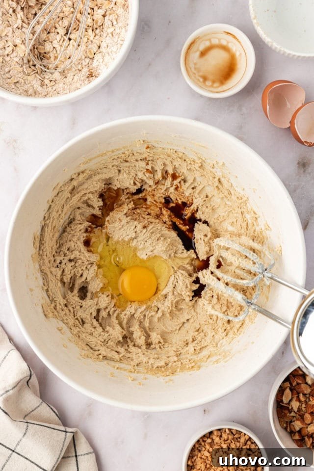 Overhead view of an egg and vanilla extract being added to the creamed butter and sugar mixture.