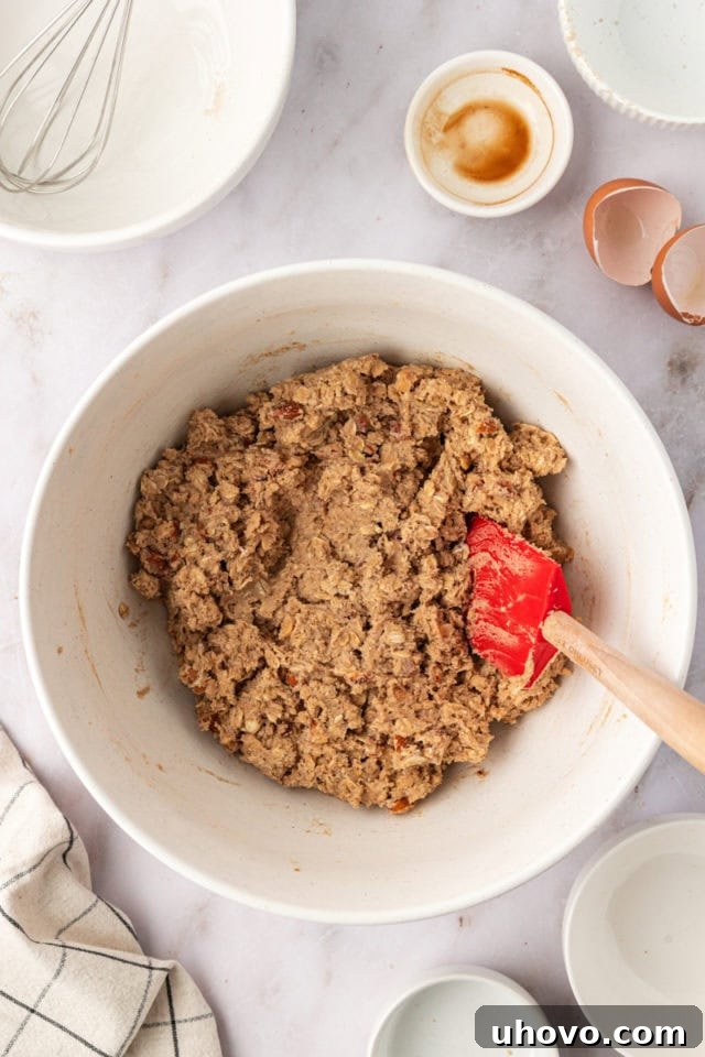 Overhead view of the finished toffee almond oatmeal cookie dough in a white mixing bowl, perfectly combined.