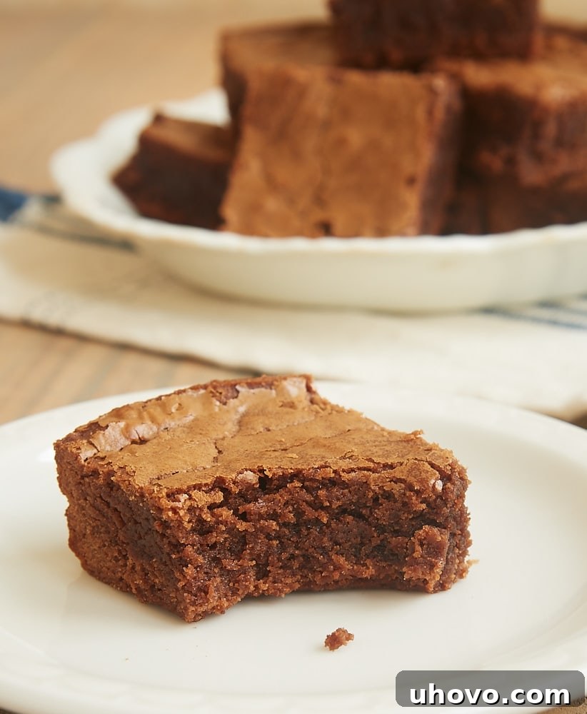 A single fudgy Milk Chocolate Brownie on a plate with a bite taken out of the corner, revealing its moist interior.