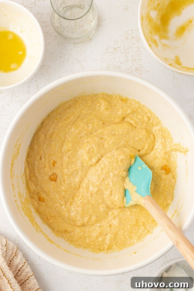 Overhead view of the sour cream corn bread batter in a white mixing bowl after wet and dry ingredients have been gently stirred together.
