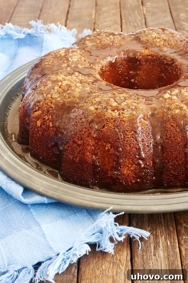 A stunning Pecan Pie Bundt Cake presented on a sophisticated pewter cake plate, showcasing its beautiful golden-brown crust and intricate Bundt shape.