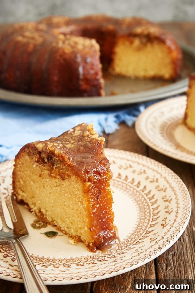 A close-up shot of a single slice of Pecan Pie Bundt Cake on a brown floral plate, showing the rich texture and nutty topping.