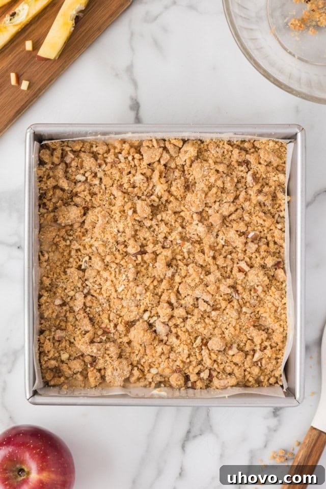 overhead view of caramel apple crumb cake in a square baking pan ready to go into the oven