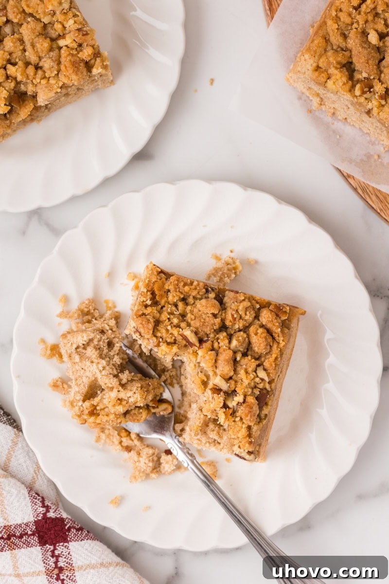 overhead view of a slice of caramel apple crumb cake on a white plate with a bite on a fork