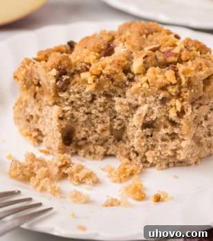 a slice of caramel apple crumb cake with a bite missing, served on a white plate