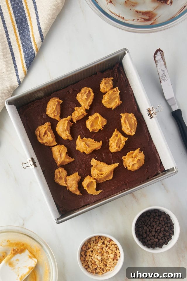 Overhead view of peanut butter dolloped onto brownie batter