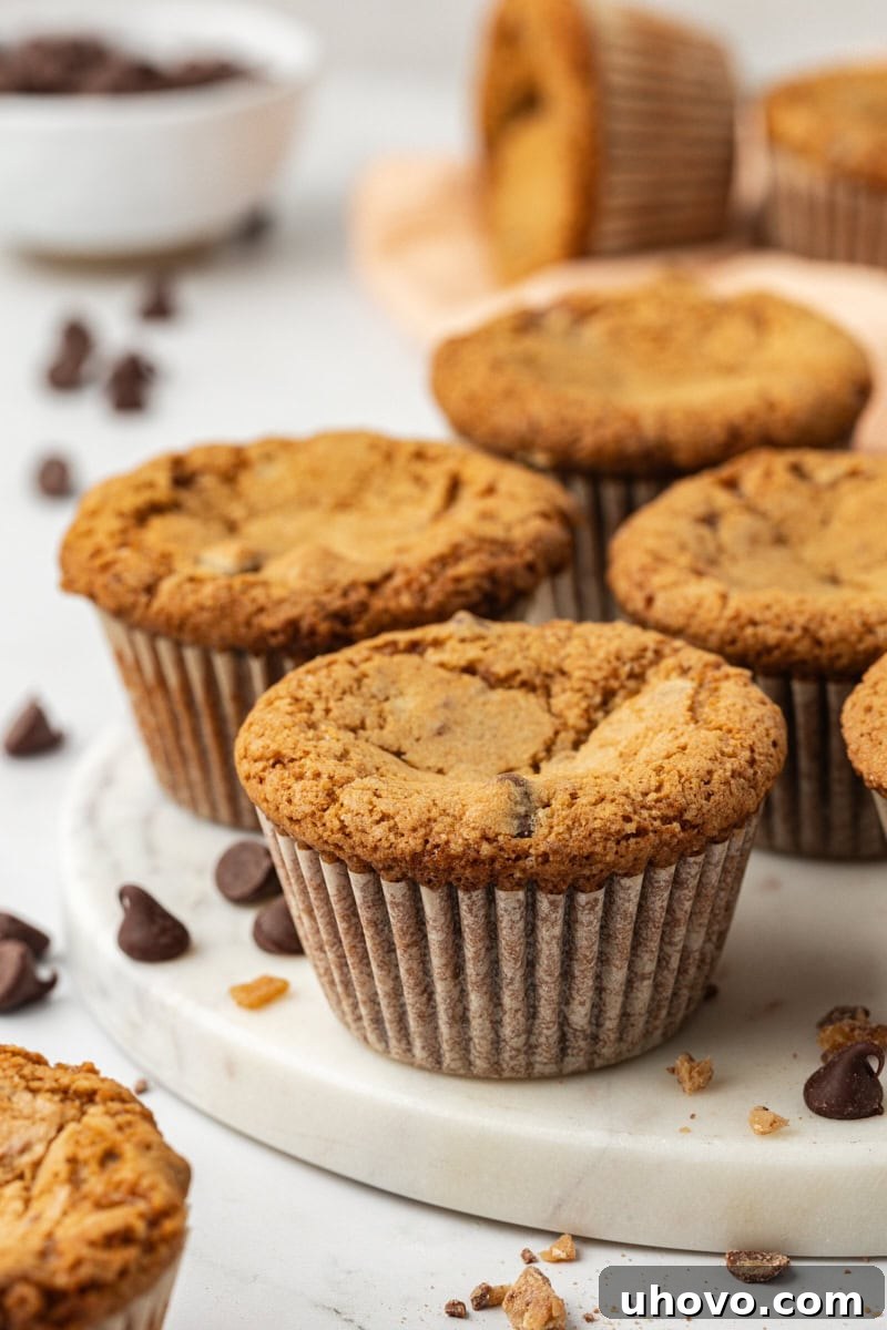 A stunning display of several golden-brown blondie cupcakes, generously studded with melted chocolate chips and crunchy toffee bits, resting on an elegant marble tray. Perfect for parties and gatherings.