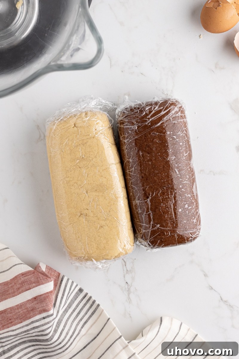 overhead view of vanilla and chocolate cookie doughs shaped into thick rectangles and wrapped in plastic wrap