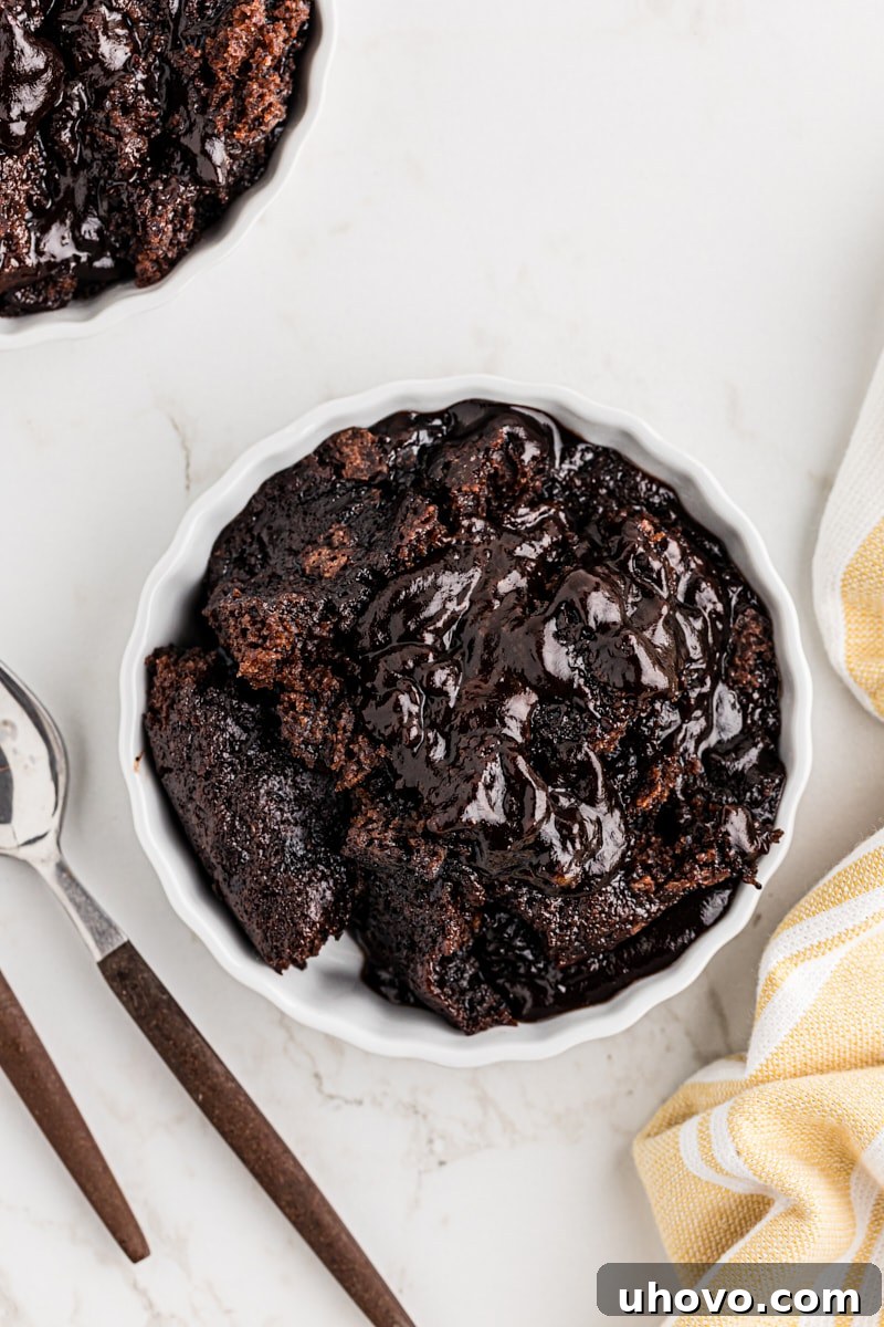Overhead view of several servings of gooey chocolate cobbler in individual ramekins, highlighting the rich cake-like top and abundant chocolate sauce.