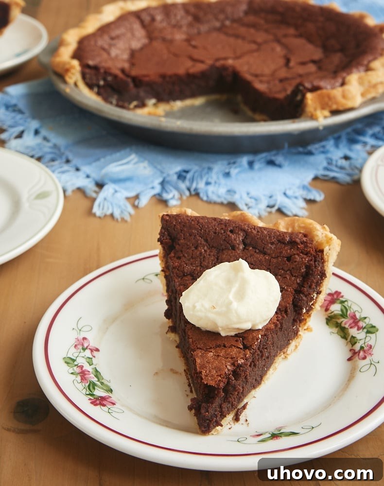 Slice of rich chocolate chess pie topped with a dollop of fluffy whipped cream