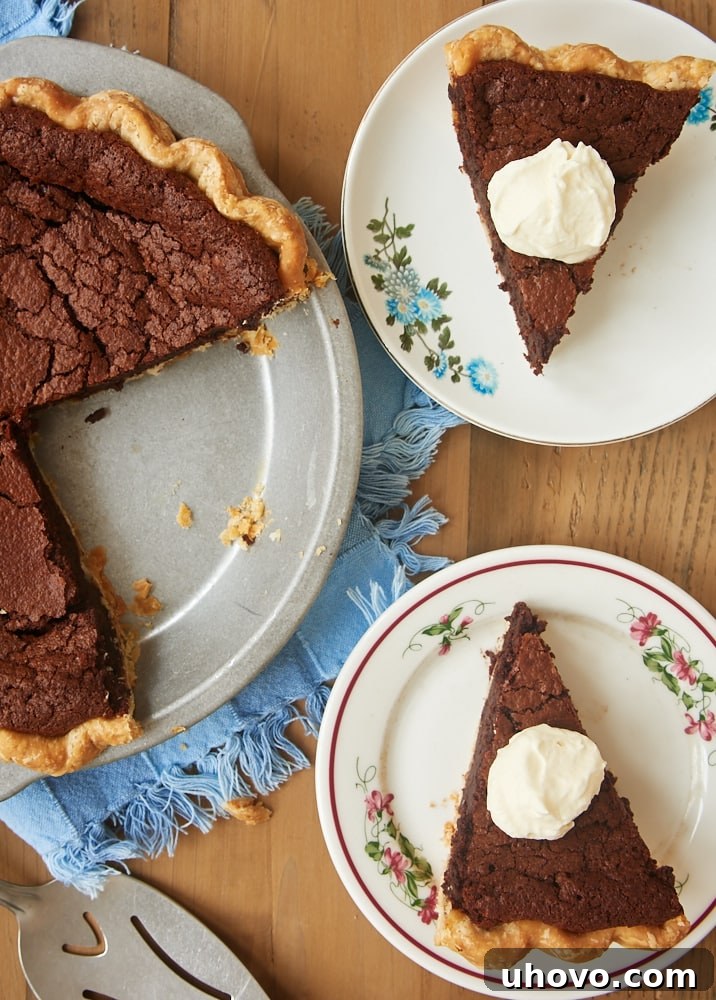 Two slices of chocolate chess pie on white plates, garnished with fresh whipped cream