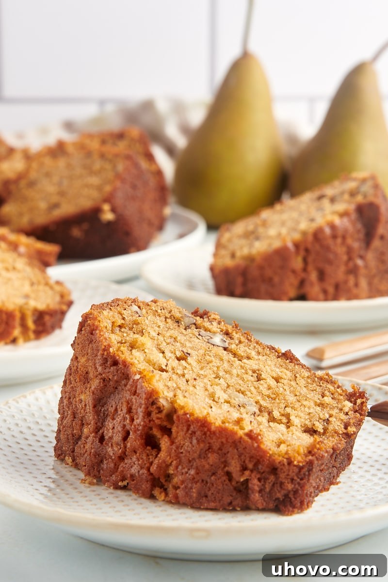 Slice of pear bread on plate with additional plates of bread and pears in background