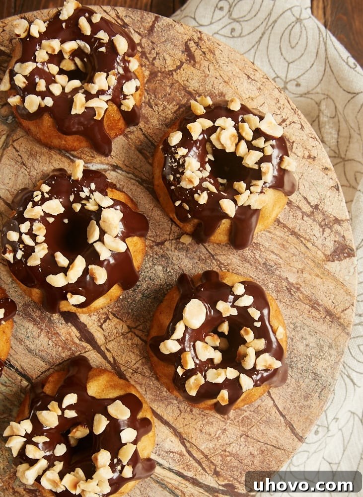 Beautifully garnished Brown Butter Hazelnut Bundt Cakes, topped with a generous drizzle of dark chocolate ganache and a sprinkle of chopped hazelnuts.