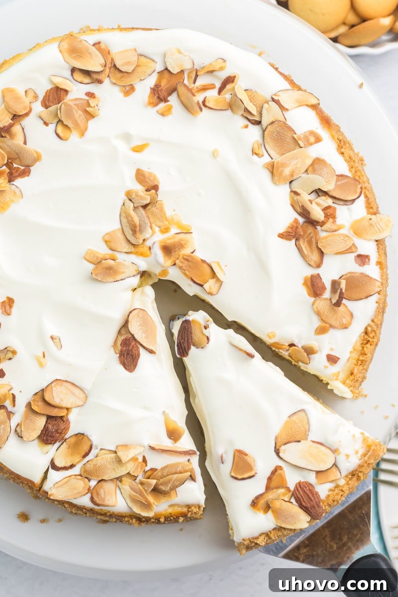 A slice of Amaretto Cheesecake is being delicately removed from the main cheesecake with a pie server, showcasing its rich layers and tempting texture.