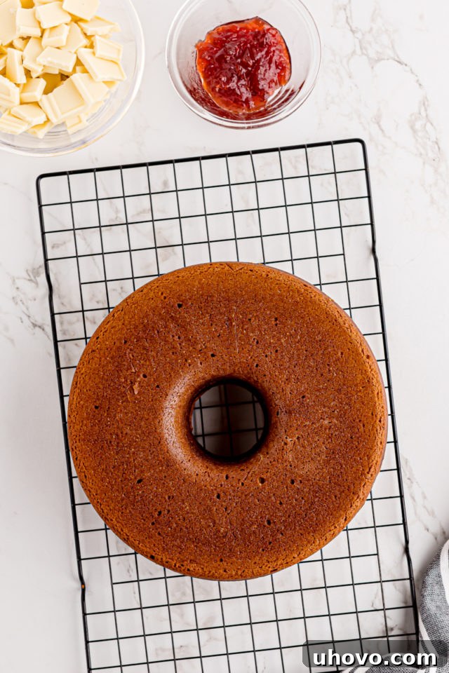 A baked cream cheese pound cake, perfectly golden, cooling completely on a wire rack after being removed from its pan.