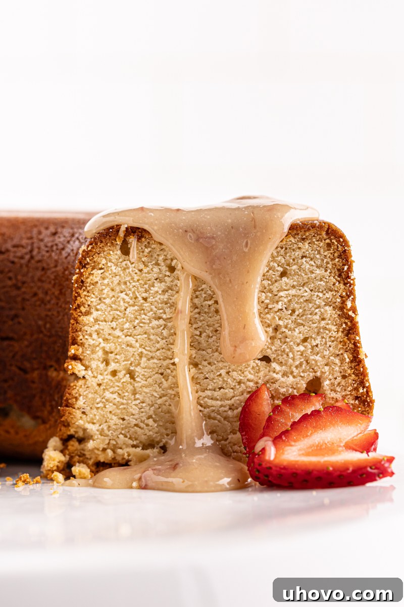 A stunning cream cheese pound cake adorned with a glistening strawberry white chocolate sauce and fresh, vibrant strawberries, creating an irresistible dessert.