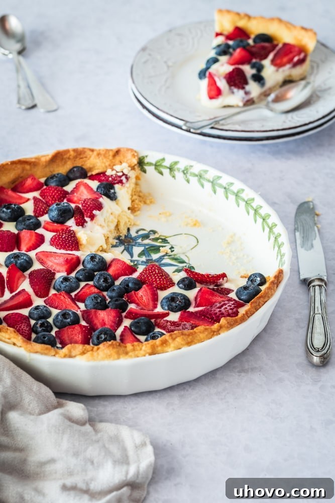partially cut Fresh Berry Tart in a white tart pan