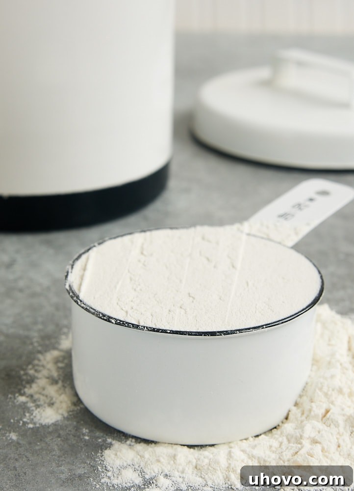 A measuring cup filled with flour using the spoon and sweep method, a reliable technique for accurate flour measurement without a scale.