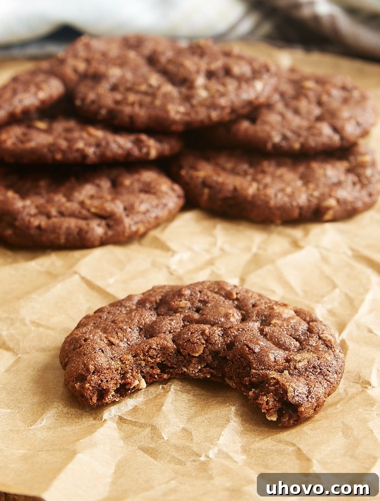 A close-up of a Chocolate Oatmeal Biscoff Cookie with a bite taken out, revealing its soft, chewy interior.