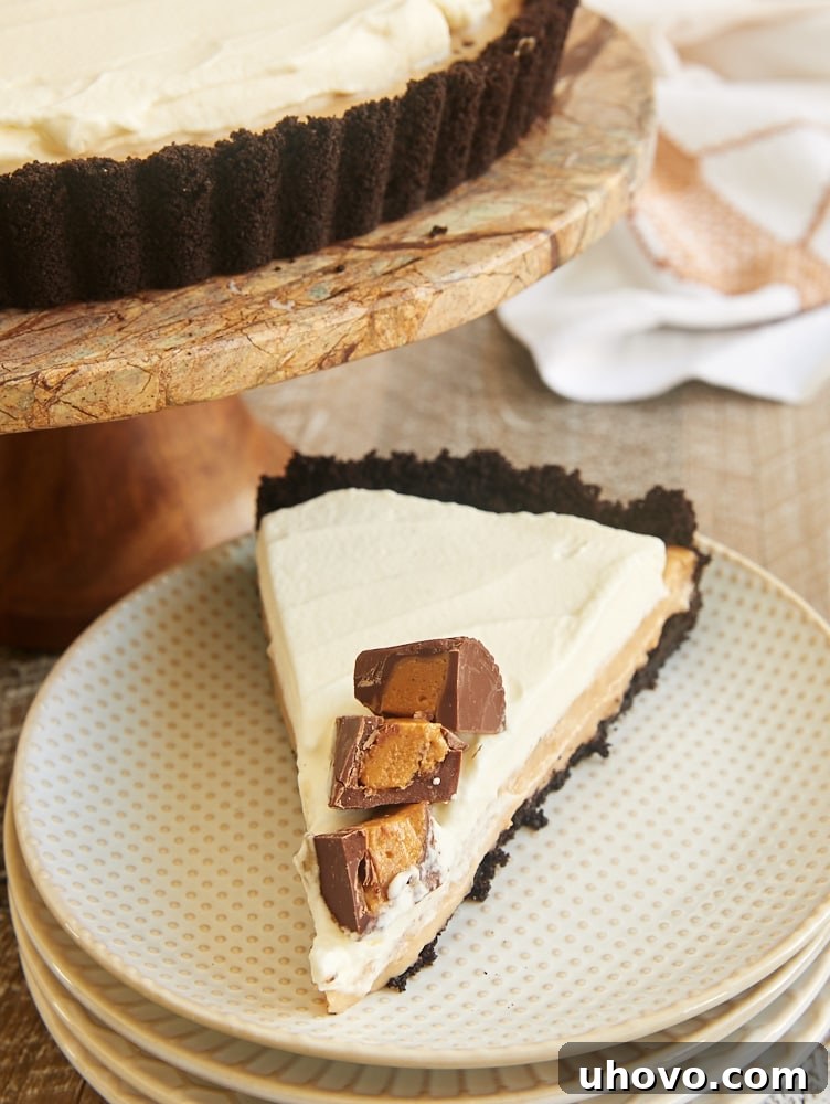 A delectable slice of Peanut Butter Pudding Pie on a white and beige plate, showcasing its creamy layers.