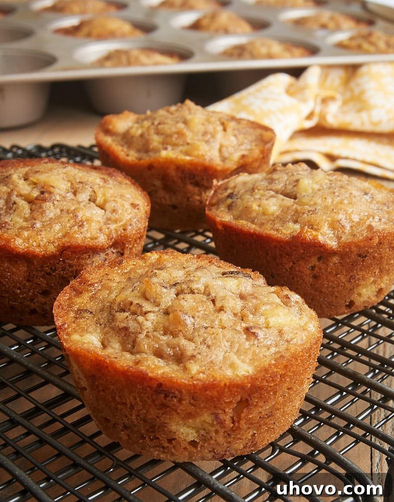 Close-up of freshly baked Pineapple Coconut Banana Nut Muffins cooling on a wire rack, showcasing their fluffy tops and golden hue.