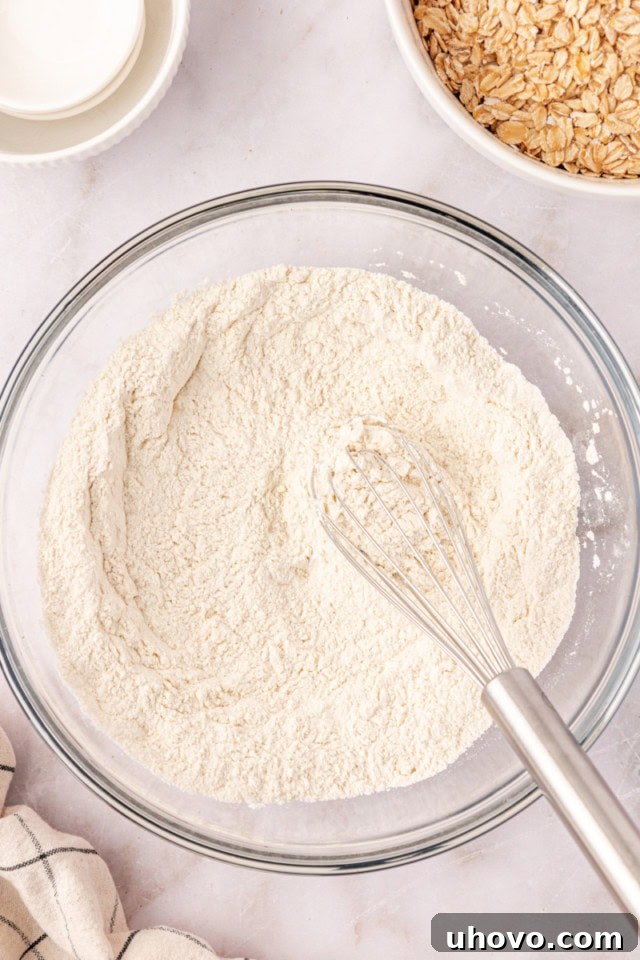 Overhead view of flour, baking powder, baking soda, and salt mixed in a bowl for oatmeal chocolate chip cookies.
