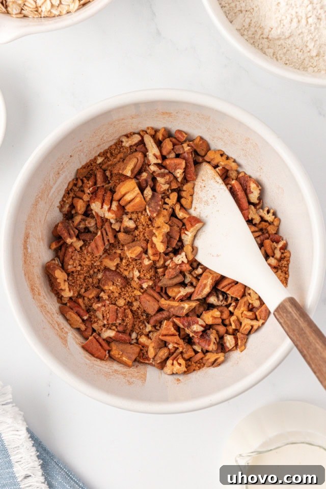 Overhead view of a bowl containing chopped pecans, brown sugar, and ground cinnamon, ready to be mixed for the swirl.