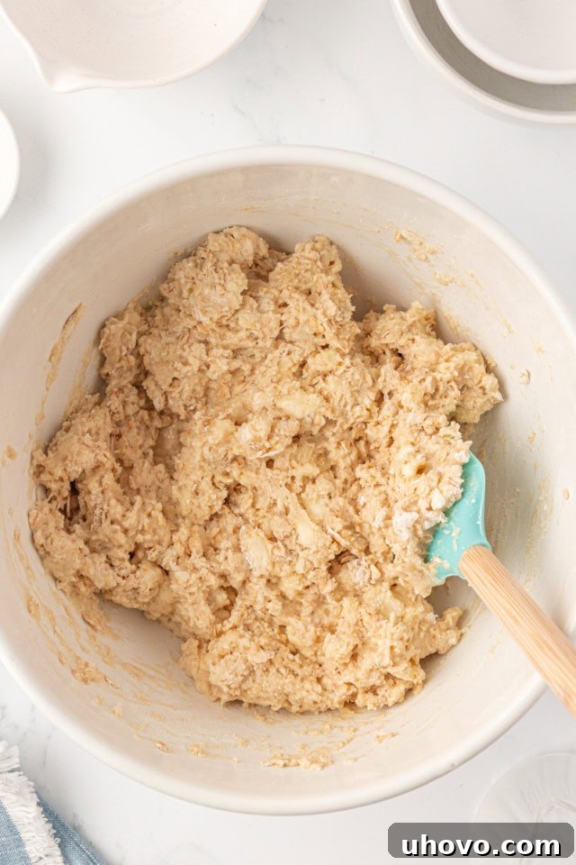 Overhead view of scone dough in a white mixing bowl, just combined and slightly shaggy, indicating it's not overmixed.