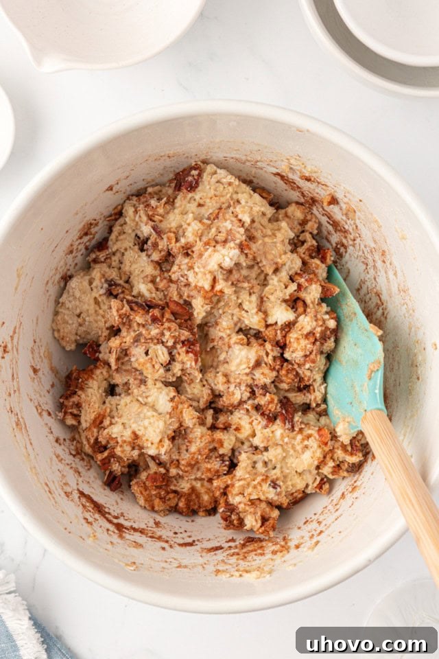 Overhead view of scone dough with the cinnamon-pecan swirl mixture gently folded in, showing visible streaks of cinnamon.
