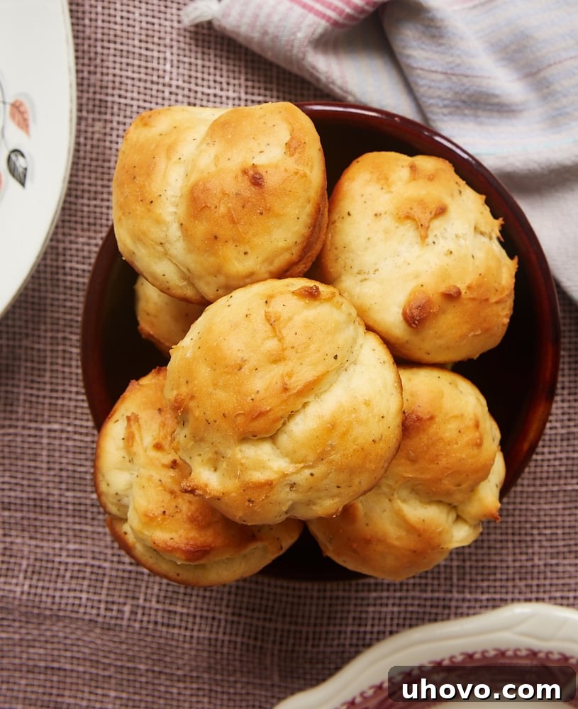 Overhead view of a bowl filled with golden-brown Cracked Pepper Sour Cream Rolls, showcasing their appealing texture and rustic charm.