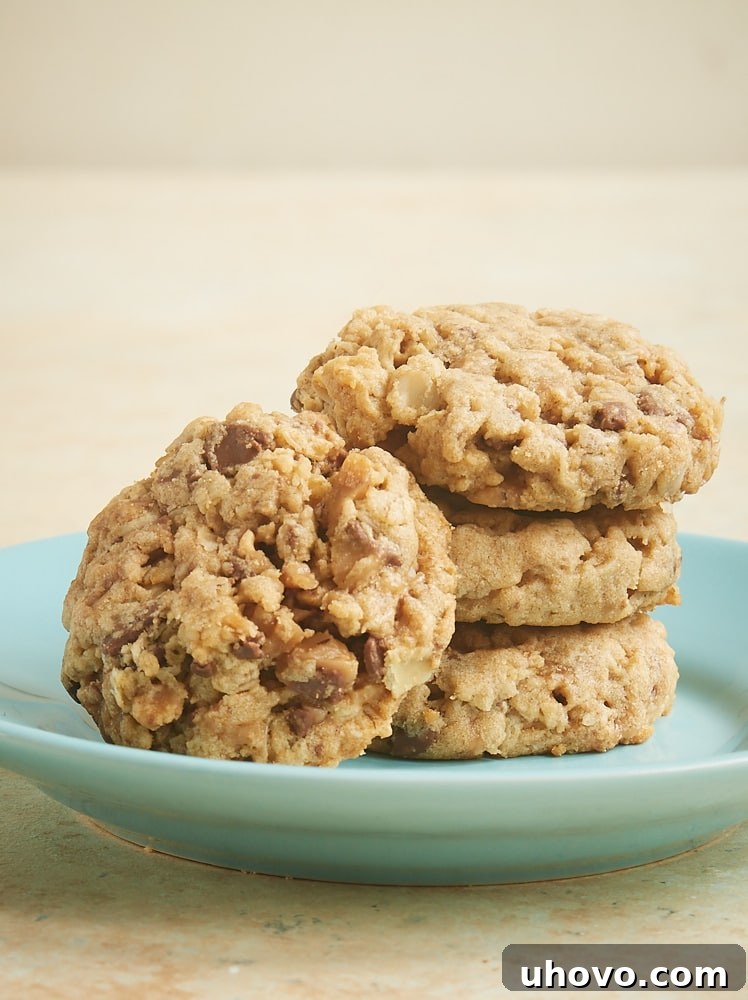 A close-up shot of a stack of Peanut Butter Toffee Oatmeal Cookies, showcasing the generous distribution of crunchy toffee pieces within.