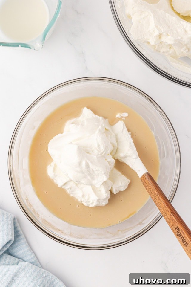 overhead view of whipped cream added to condensed milk mixture for stracciatella ice cream