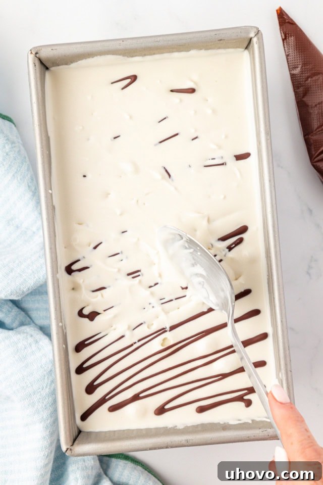 overhead view of a spoon breaking up hardened chocolate into stracciatella ice cream