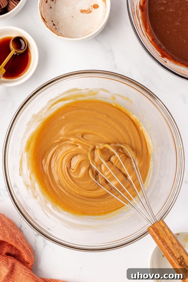 The second glass mixing bowl, seen from above, holds a smooth, creamy peanut butter ice cream base, thoroughly mixed and ready for the next step.