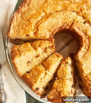 A delicious overhead view of a partially sliced Chocolate Chip Cream Cheese Pound Cake on a white plate, ready to be enjoyed with its chocolate chips visible.
