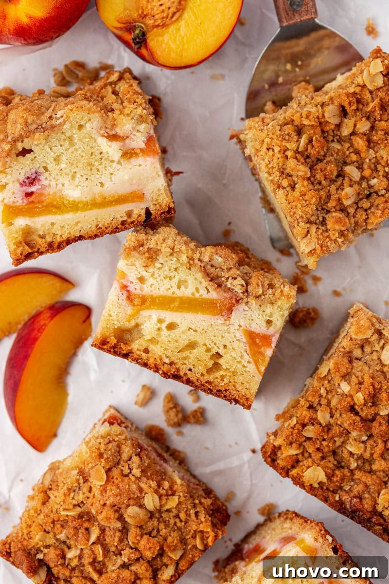 An artistic overhead arrangement of beautifully sliced peach coffee cake alongside perfectly fanned fresh peach slices, all presented on a pristine white surface, highlighting the cake's fresh ingredients.
