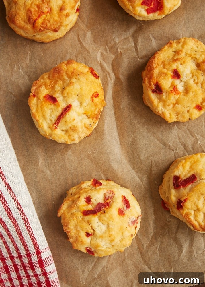 Freshly baked Pimiento Cheese Biscuits cooling on parchment paper, showcasing their golden-brown tops and tender texture.